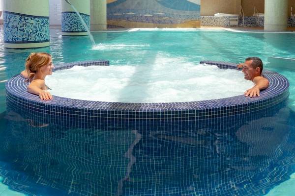 Ein Mann und eine Frau entspannen sich in einem Whirlpool im Secrets Bahia Real Resort & Spa.