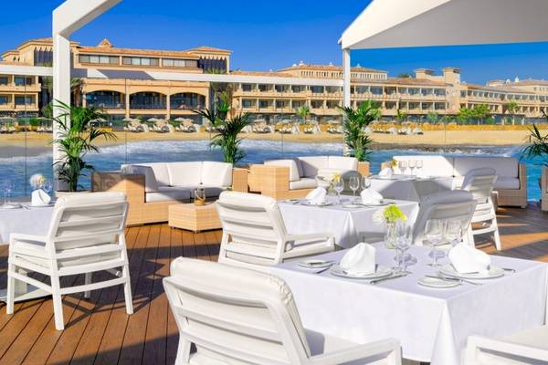 Gedeckter Tisch auf einer Terrasse am Strand vor dem Secrets Bahia Real Resort & Spa Hotel.