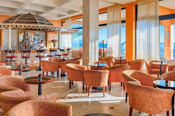 Loungebereich des Secrets Bahia Real Resort & Spa mit Bar, Tischen und Stühlen.
