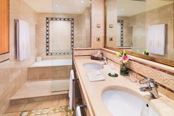 Luxuriöses Badezimmer mit Doppelwaschbecken, Badewanne, Spiegel und Marmorboden.