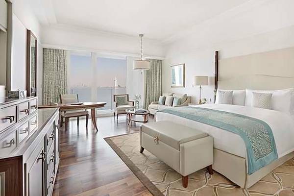 Innenansicht einer Suite im Waldorf Astoria Dubai Palm Jumeirah mit großem Bett, Schreibtisch und Blick auf das Meer.