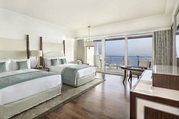 Innenansicht der Suite im Waldorf Astoria Dubai Palm Jumeirah mit zwei Betten, Meerblick und modernem Interieur.