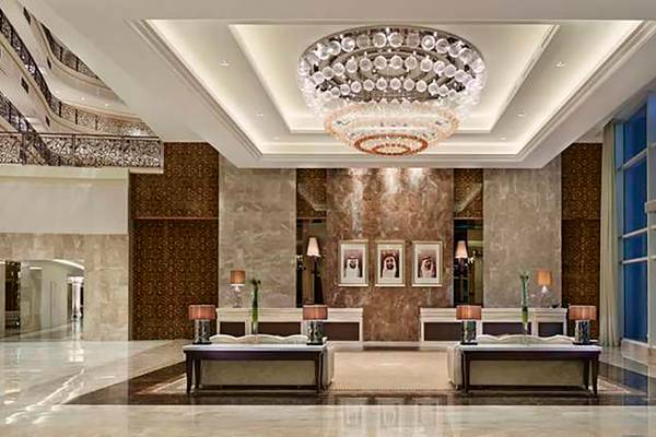 Lobby des Waldorf Astoria Dubai Palm Jumeirah Hotels mit einer großen Kristallleuchte und Marmorwänden.