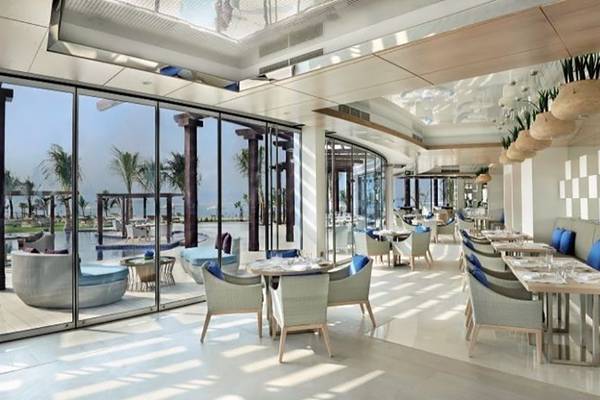 Innenansicht des Restaurants im Waldorf Astoria Dubai Palm Jumeirah mit großen Glaswänden und Meerblick.