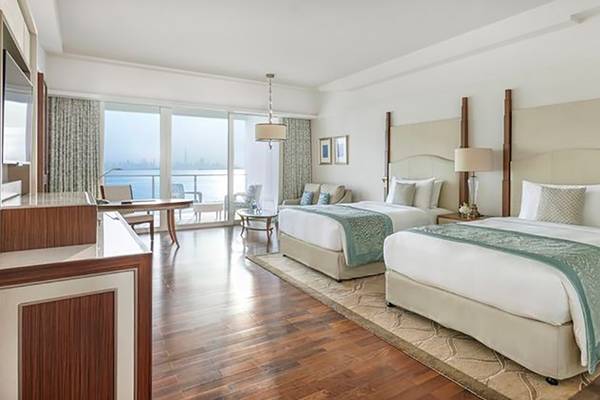 Innenansicht einer Suite im Waldorf Astoria Dubai Palm Jumeirah mit zwei Betten, Schreibtisch und Meerblick.