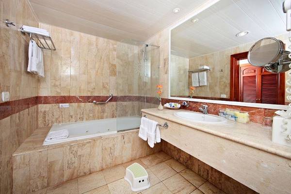 Ein Badezimmer im Bahia Principe Grand Turquesa mit Badewanne, Dusche, Waschbecken und Spiegel.