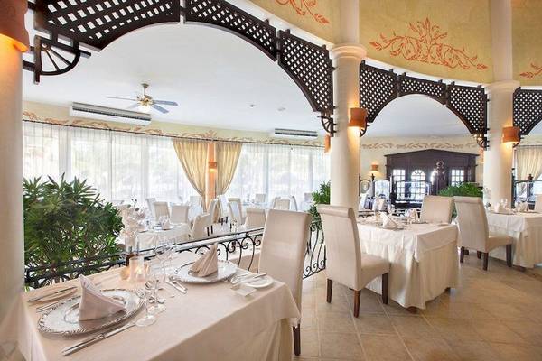 Innenansicht des Restaurants Bahia Principe Grand Turquesa mit gedeckten Tischen und Stühlen.