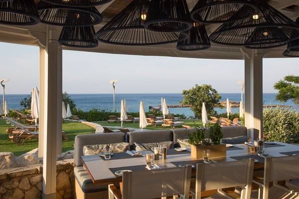 Außenbereich des Capo Bay Hotels mit Tisch und Blick auf das Meer.