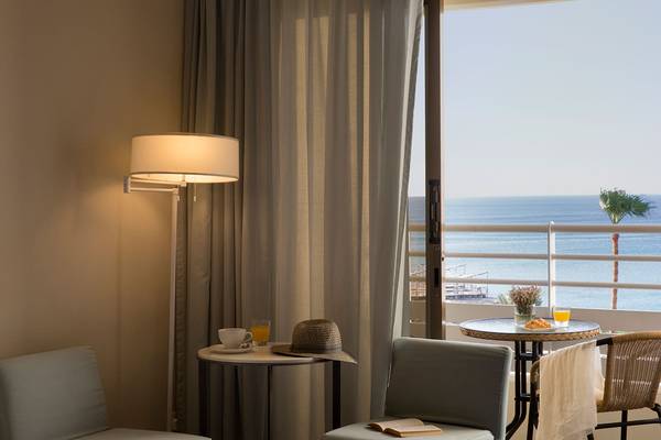 Balkonansicht im Capo Bay Hotel mit Meerblick, Tisch, Stühlen, Lampe und Dekoration.