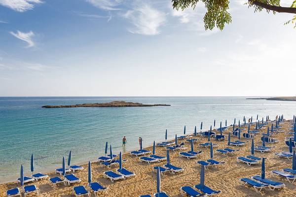 Blick auf den Strand des Capo Bay Hotels mit vielen Liegen und Sonnenschirmen.