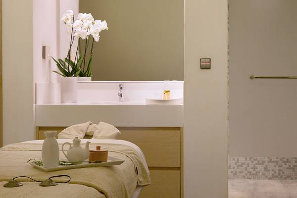 Spa-Behandlungsraum im Capo Bay Hotel mit Tisch, weißen Vasen und Orchideen.