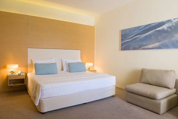 Doppelbett in einem eleganten Zimmer im Capo Bay Hotel mit einem Gemälde an der Wand.