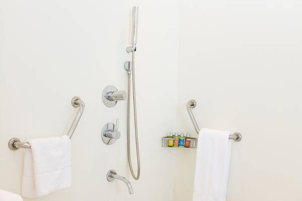 Barrierefreie Dusche im Capo Bay Hotel mit Handtüchern und Haltegriffen.