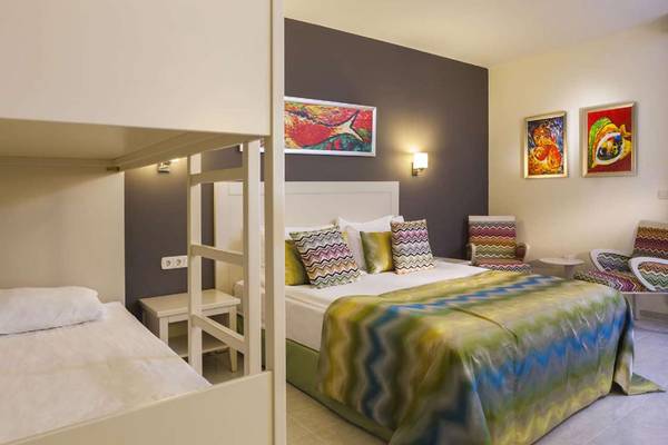 Schlafzimmer im Magic Life Belek Hotel mit Doppelbett, Stockbett, Nachttischen und bunten Gemälden.