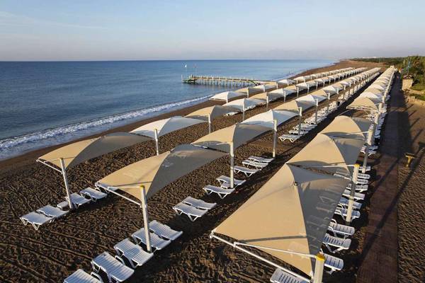 Luftaufnahme von weißen Sonnenliegen mit Sonnenschirmen am Magic Life Belek Strand