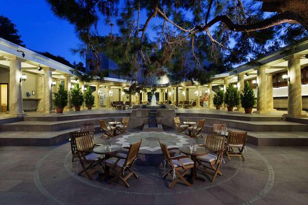 Außenbereich des Magic Life Belek Hotels bei Nacht mit runden Tischen und Stühlen.