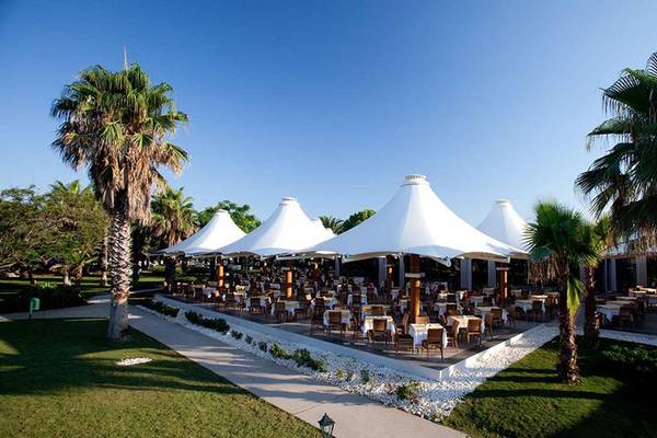Außenrestaurant des Magic Life Belek Hotels mit weißen Zelten und umliegenden Palmen.