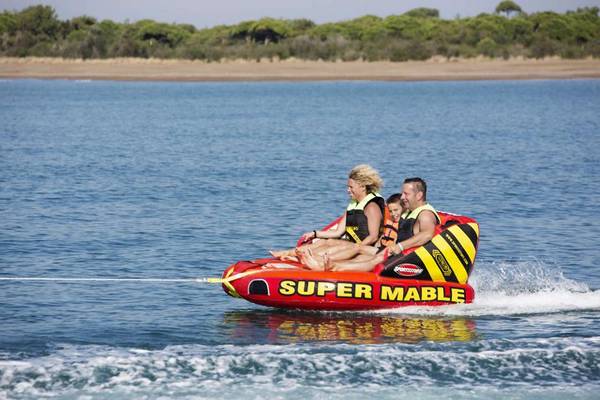 Drei Leute auf einem aufblasbaren Boot auf dem Wasser, das Super Mable liest.