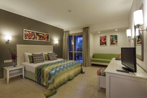 Ein Hotelzimmer im Magic Life Belek mit einem großen Bett, Fernseher, und einem grünen Sofa.