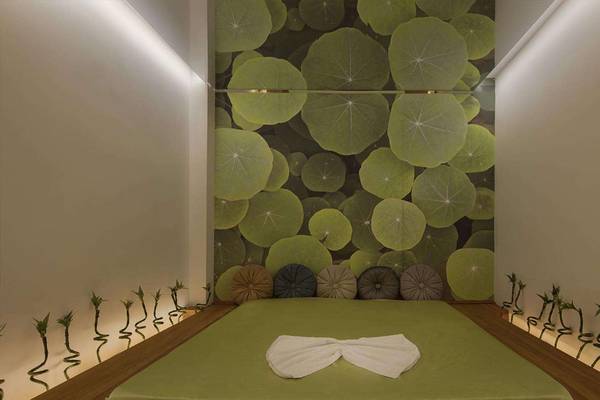 Zimmer im Magic Life Belek Hotel mit grünem Bett und Lotus-Wandtapete.