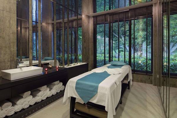 Spa-Behandlungsraum im Magic Life Belek Hotel mit Massageliege, Waschbecken und Blick auf den Garten.