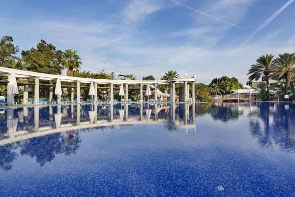 Außenpool des Magic Life Belek Hotels mit weißen Sonnenliegen und Schirmen.