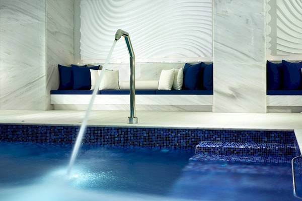 Ein modernes Spa-Pool-Gebiet im Petasos Beach Resort & Spa mit blauen Kissen und Marmorwänden.