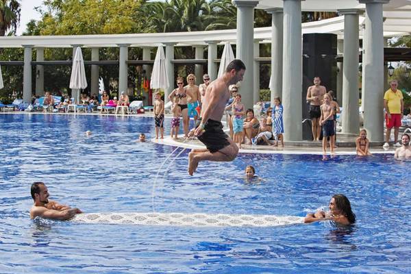 Ein Mann springt in den Pool des Magic Life Belek Hotels, während andere Gäste beobachten.