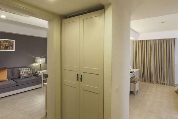 Innenansicht eines Zimmers im Magic Life Belek Hotel mit Sofa, Nachttisch, Lampe und Bett.