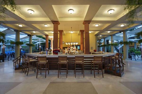 Bar im Magic Life Belek Hotel mit Holzstühlen und einer langen Theke.