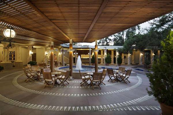 Außenterrasse des Magic Life Belek Hotels mit runden Tischen, Stühlen und einem zentralen Brunnen.