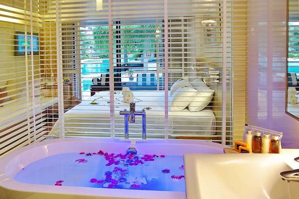 Badezimmer des DoubleTree by Hilton Phuket Banthai Resort mit Badewanne und Blick auf das Bett und den Pool.