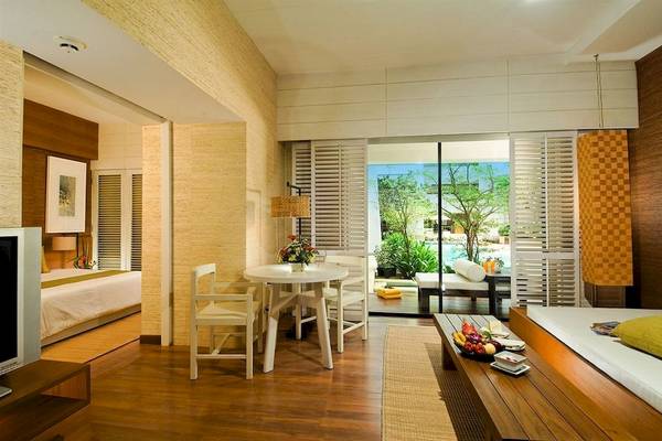 Doppelzimmer im DoubleTree by Hilton Phuket Banthai Resort mit Tisch, Stühlen und Blick auf den Pool.