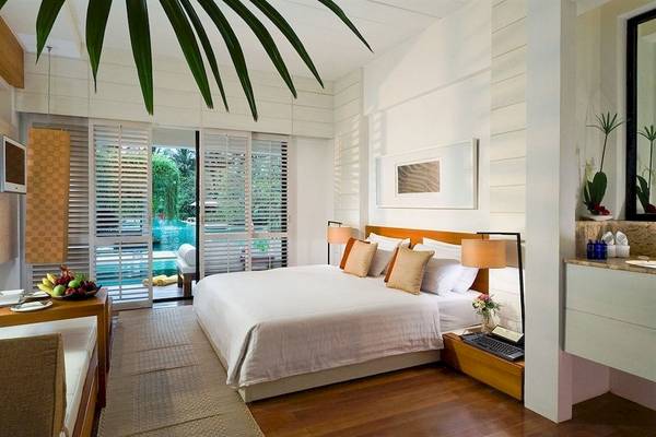 Schlafzimmer im DoubleTree by Hilton Phuket Banthai Resort mit Kingsize-Bett, Fernseher und Obstteller.
