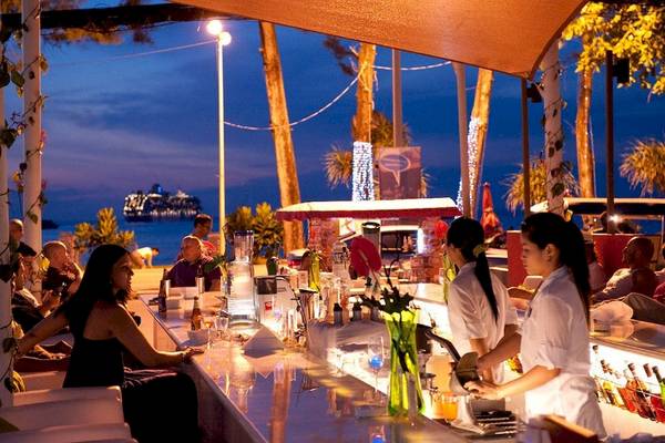 Bar im DoubleTree by Hilton Phuket Banthai Resort bei Nacht mit Gästen und Blick aufs Meer.