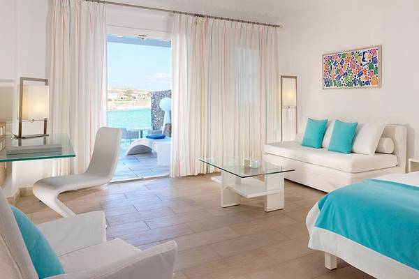 Innenansicht eines Zimmers im Petasos Beach Resort mit Blick auf das Meer, weiße Möbel und türkisfarbene Akzente.