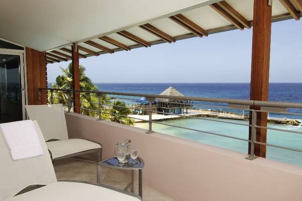 Balkon im Avila Beach Hotel mit Meerblick, zwei Liegestühlen und einem Tisch mit Getränken.