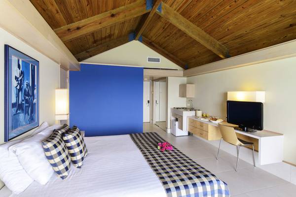 Innenansicht eines Zimmers im Avila Beach Hotel mit Bett, Schreibtisch, Fernseher und blauer Wand.