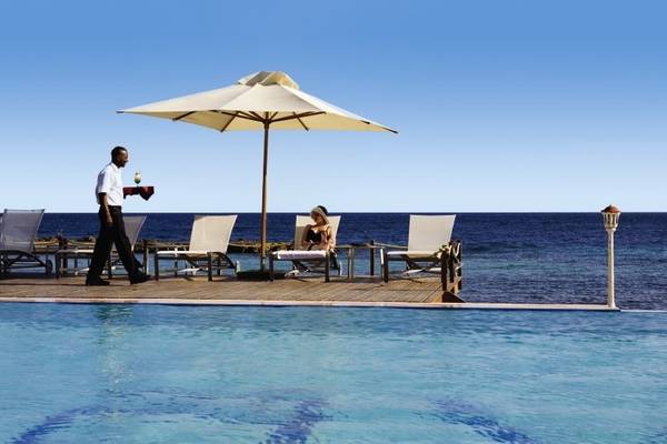Am Avila Beach Hotel genießt eine Frau den Poolbereich, während ein Mann serviert.