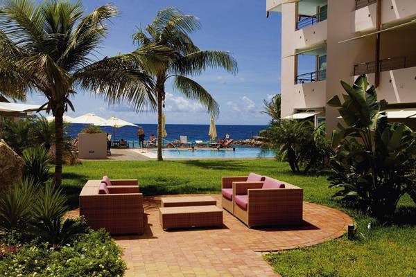 Gartenbereich des Avila Beach Hotels mit Sofas, Tischen und Blick auf den Ozean.