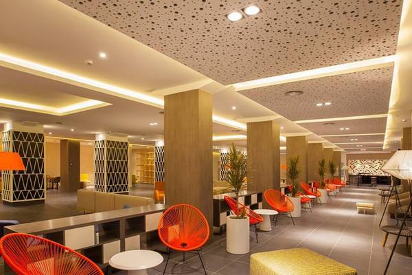 Innenbereich des Abora Catarina Hotel mit roten Stühlen und Tischen, Pflanzgefäßen und gefliestem Boden.