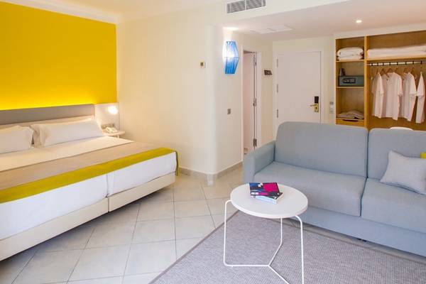 Innenansicht eines Zimmers im Abora Catarina Hotel mit Bett, Sofa, Tisch und Kleiderschrank.