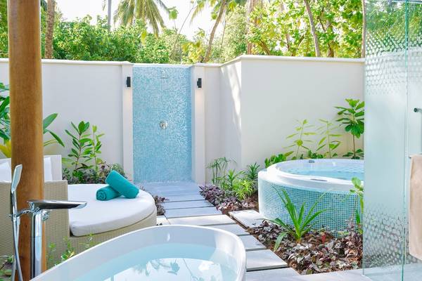 Außenbereich des Kandima Maldives Hotels mit Badewanne und Jacuzzi im Freien.