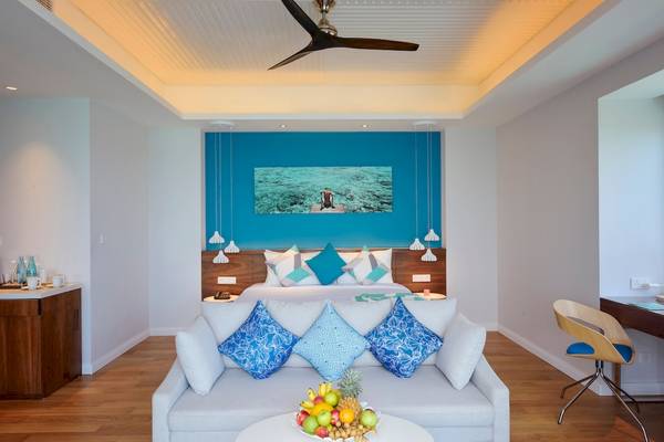 Hotelzimmer im Kandima Maldives mit einem Bett und einer Couch, die einen Blick auf das Meer bieten.
