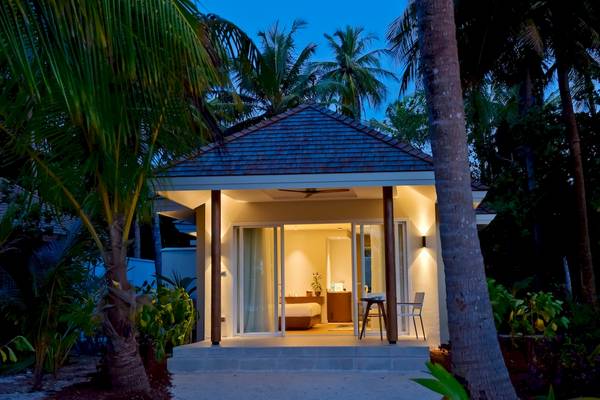 Nachtansicht des Kandima Maldives Hotels mit Außenbeleuchtung und beleuchtetem Schlafzimmer.