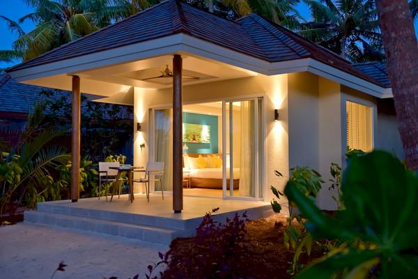 Abendblick auf eine Villa im Kandima Maldives mit Außentisch und gut beleuchteter Veranda.