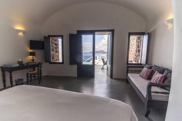 Innenansicht eines Schlafzimmers im Ambassador Aegean Luxury Hotel & Suites mit offenem Balkon und Meerblick.