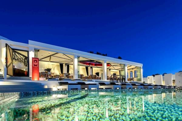 Abendlicher Blick auf das Ambassador Aegean Luxury Hotel & Suites mit Swimmingpool und Loungebereich.