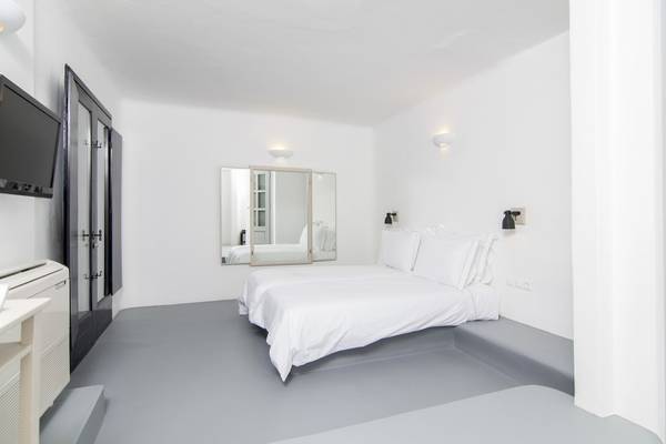 Schlafzimmer im Ambassador Aegean Luxury Hotel & Suites mit weißem Bett, Spiegel und Fernseher.