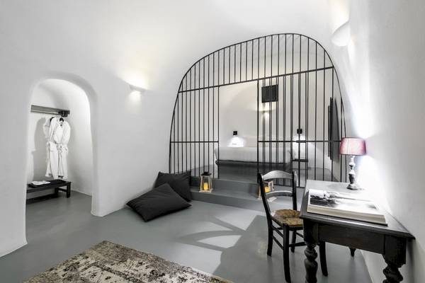 Innenansicht des Ambassador Aegean Luxury Hotel & Suites mit einem Bett, einem Schreibtisch und einem weißen Badezimmer.